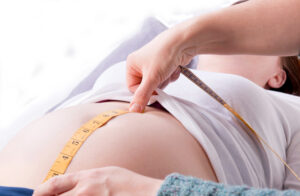 midwife checking measuring a pregnant mothers belly