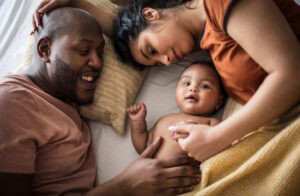 Family bonding time. African American parents with daughter on bed.